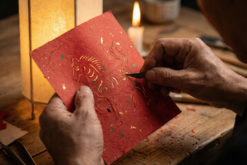 Artisan Hands Crafting a Golden Horse Design on Red Paper by Candlelight