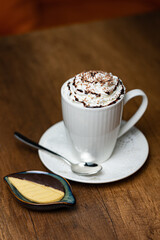 Whipped Cream Coffee Latte in White Mug With Chocolate Drizzle and Shavings, Fresh Cookie Side
