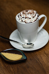 Whipped Cream Coffee Latte in White Mug With Chocolate Drizzle and Shavings, Fresh Cookie Side