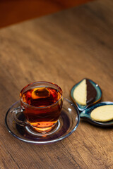 Cozy Tea Time With Amber Tea In Glass Cup And Ceramic Leaf Plates On Wooden Table