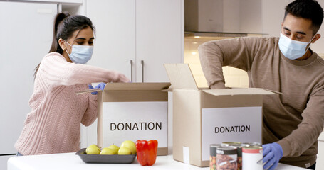 Couple, donation and packing boxes for food drive, support or charity with face mask in home....