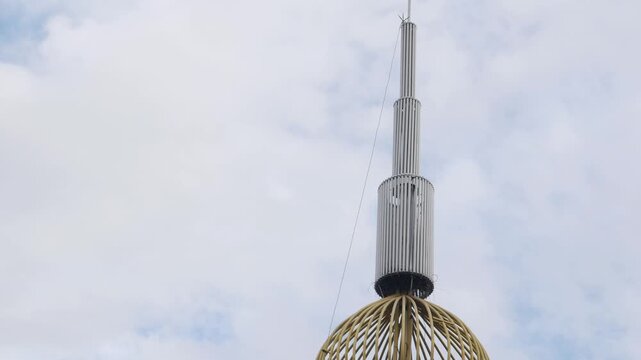 Close up of golden lattice dome and loudspeakers on Islamic minaret tower against a blue cloudy sky, religion announcement concept.