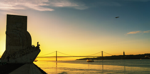 Golden hour waterfront cityscape with monumental silhouette calm river reflections and suspension bridge a ferry gliding across warm water and an airplane carving a path of freedom and journey