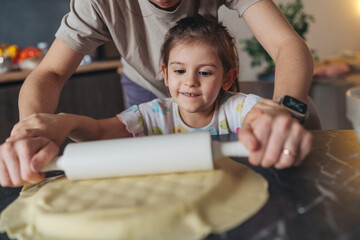 Smiling youngster collaborates with guardian to make pastry together