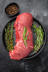 Fresh raw beef meat with rosemary and thyme prepared for roasting. High quality protein for homemade roast beef and gourmet dishes.