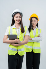 A vertical photograph of Asian female engineers collaboratively reviewing digital blueprints symbolizes the AI-driven construction ecosystem, future industry skills, teamwork, and professionalism.