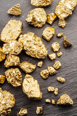 Gold nuggets on black stone background top view. Imitation of gold nuggets.