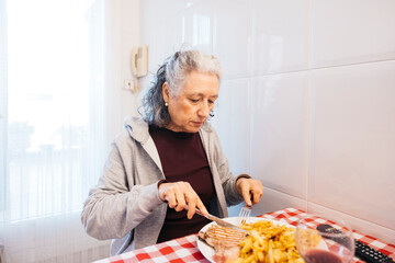 Senior woman enjoying lunch by herself in a bright kitchen