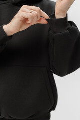 Hands adjusting cuff of black sweatshirt during indoor activity in a casual setting