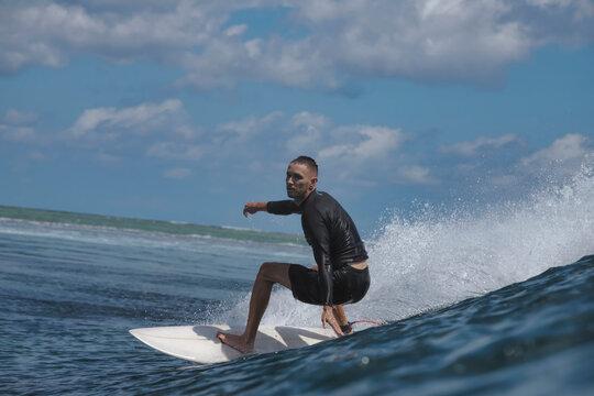 Surfer Riding Ocean Wave, Spray Arching As Board Carves Crest