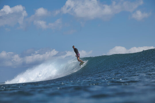 Surfer Riding Ocean Wave, Spray Arching As Board Carves Crest