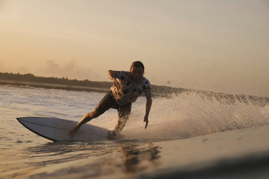 Surfer Carving Low Spray Illuminated Close Foreground Perspective