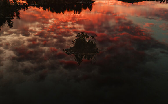Island in beautiful lake with reflection of vibrant sunrise, Maine