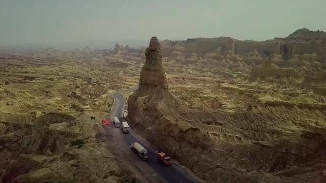 Cinematic drone shot moving above of road and mountain in buzi pass top with trucks Makran coastal Highway Balochistan, Pakistan