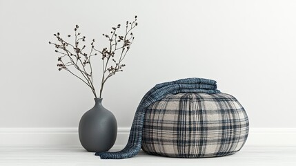 Still life vase, dried plant, plaid pouf, and soft blanket