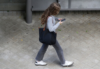Chica adicta usando tel&eacute;fono m&oacute;vil con nomofobia y adicci&oacute;n virtual mirando al suelo