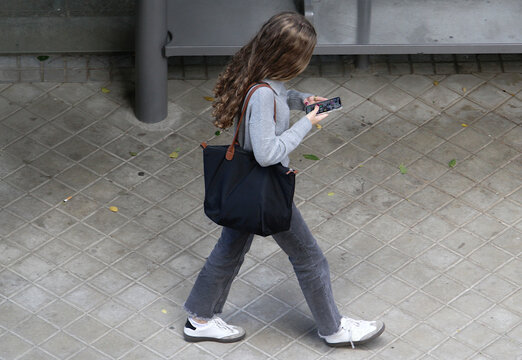Chica adicta usando tel&eacute;fono m&oacute;vil con nomofobia y adicci&oacute;n virtual mirando al suelo