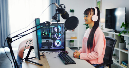 Teenager, gaming and computer with microphone for girl, esports and online hobby in home. Headphones, gen z content creator or streamer with video game, tournament or internet challenge for vlog