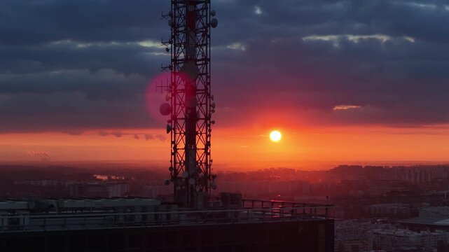 Aerial drone view of a large telecommunications tower set against an intense orange sunset over Belgrade, Serbi