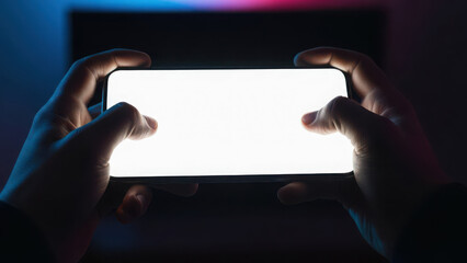 Hands holding a smartphone with a bright white screen in a dark setting.