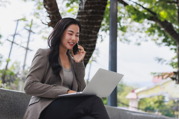 Young woman confidently working remotely using laptop and phone