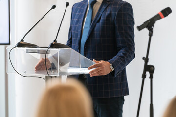 Male spokesperson giving official press statement on stage. Captures controlled communication, media focus, and formal public announcement.