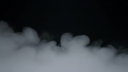 Low lying white smoke drifts across a dark black background perfect for cinematic overlays special effects or moody atmospheric design elements in video production.