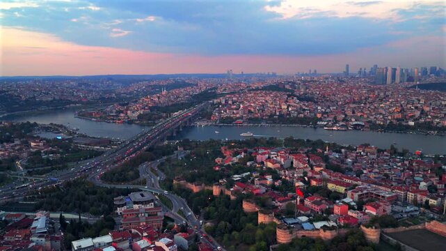 Istanbul Turkey T&uuml;rkiye aerial drone harbor view traffic cars bridge Bosphorus Strait ferry boats sunset golden hour pink sky cityscape buildings panoramic landscape skyscrapers mosque pan right