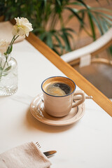 Hot black coffee served in a ceramic cup on a cozy cafe table with soft natural light
