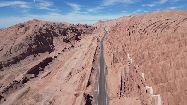San Pedro de Atacama, Chile: Aerial footage of car driving on the road between rock formation in San Pedro de Atacama, Chile on sunny day. Taken with forward motion 