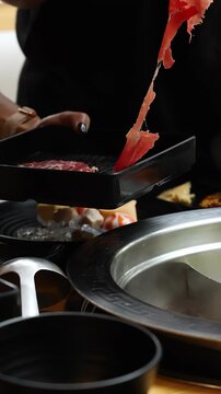 Person Cooking Beef Slice in Steaming Hotpot Restaurant