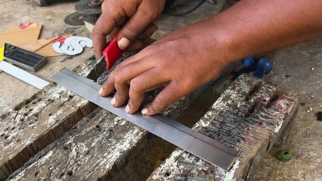 a man making parallel lines on an iron plate using a cutter knife
