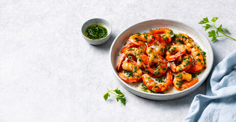 Grilled shrimps with chimichurri sauce on a white plate. Grey background. Copy space.