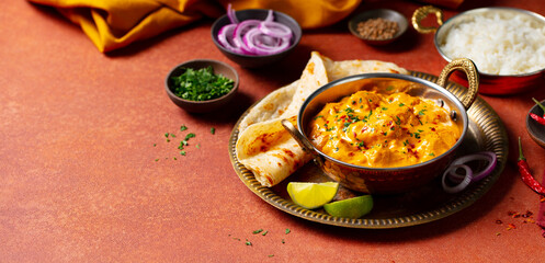 Spicy chicken curry in creamy sauce, served in a traditional bowl. Terracotta-orange background. Close up. Top view.