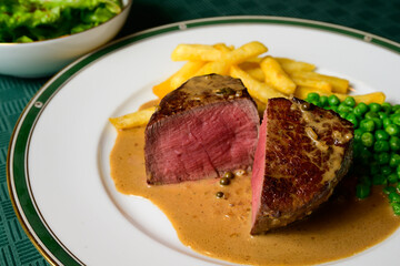 Filet Mignon Beef Steak with Green Peppercorn Sauce with French Fries and Peas called Steak au Poivre Vert in French
