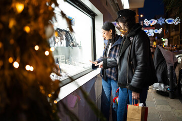 Obraz premium Women friends window shopping during a christmas night