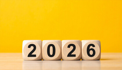 Wooden cubes displaying number 2026 against yellow wall, New Year concept, minimalist composition