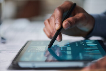 Black man using stylus interacting with digital tablet displaying data charts and graphs, close up of hand and device, focusing on technology usage in professional setting