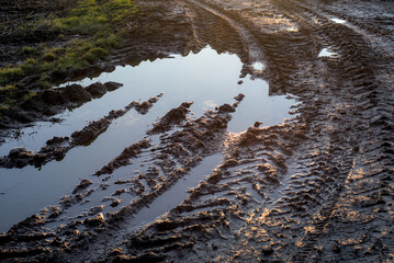 A muddy road with puddles of water.