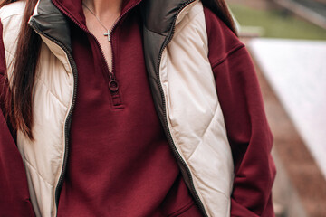 Close up women's everyday casual sport wear, beige puffer vest and brown sweater, autumn-winter stylish woman's cloth