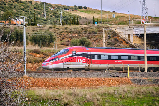 High-Speed Red Train by IRYO Passing Through Puertollano Castilla-La Mancha Spain With olive orchard on rolling hills in the Industrial Heritage Mining Landscape