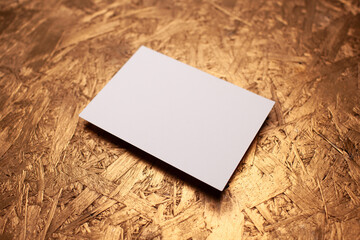 Blank greeting card mockup on textured golden surface, showcasing minimalistic design with ample copy space for personalized messages and creative artwork