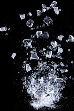 Ice cubes crushed on a black background. Flying shards of ice.
