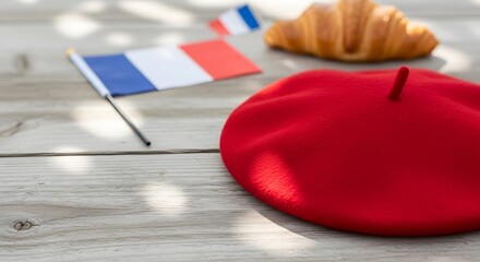 Close up of French red beret, flag, and croissant on a rustic wooden table with dappled sunlight, representing Bastille Day celebration concept