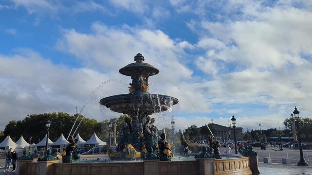 Place de la Concorde in Paris. A stunning fountain stands tall under a beautiful sky. Visitors admire the intricate details of this historical landmark.