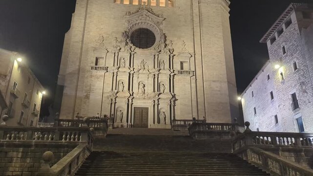 Girona Cathedral at Night. A stunning view of the illuminated facade under a starry sky. Experience the charm of this historic site in the tranquil night setting.