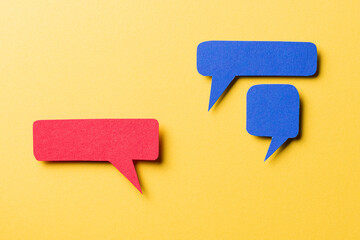 Red and blue blank paper speech bubbles with shadow and copy space for text on yellow background,...
