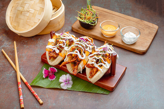 Soft steamed bao bun filled with juicy, spicy chicken and flavorful sauce. A popular Asian street food and fusion dish, known for its fluffy texture and bold taste. Ideal for restaurant menus, street 