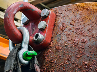Rusted metal hook showing wear at a construction site in the afternoon light with tools nearby
