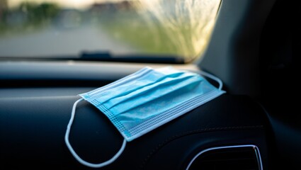 surgical mask on dashboard with dark interior contrast and highlights on pleats for clean still life